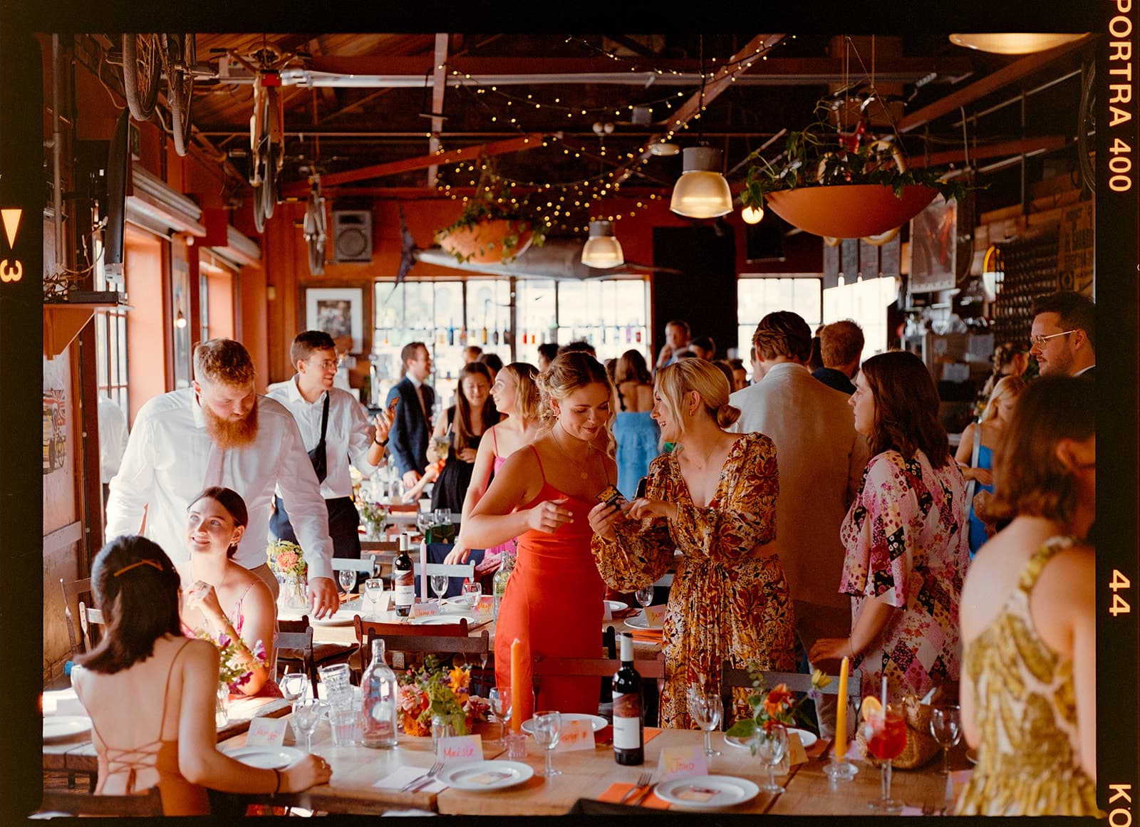 Group of people at a festive indoor gathering with tables set for dining.
