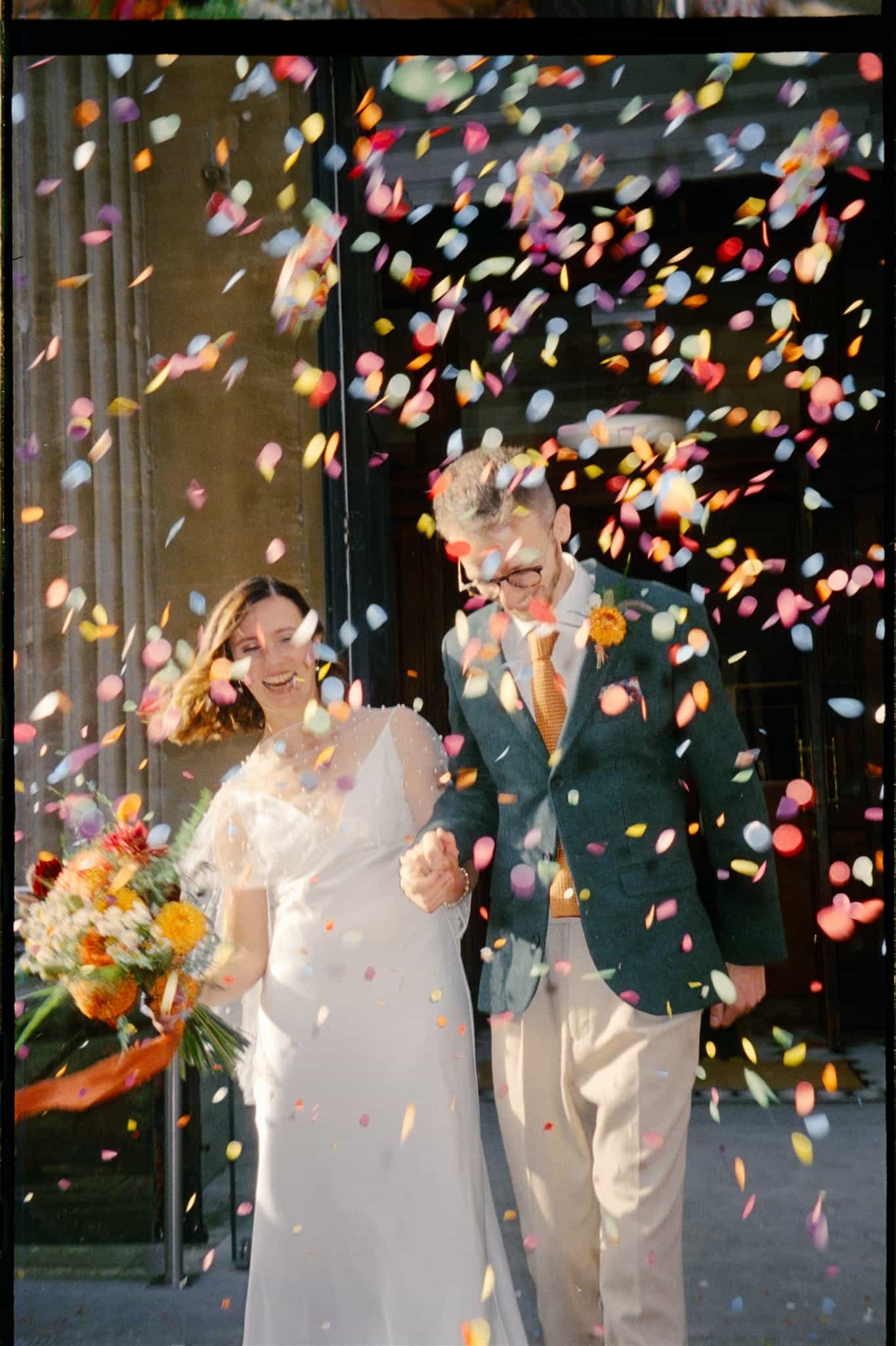A charming film photo of a bride and groom walking through confetti, celebrating their special day at Bristol Registry Office.