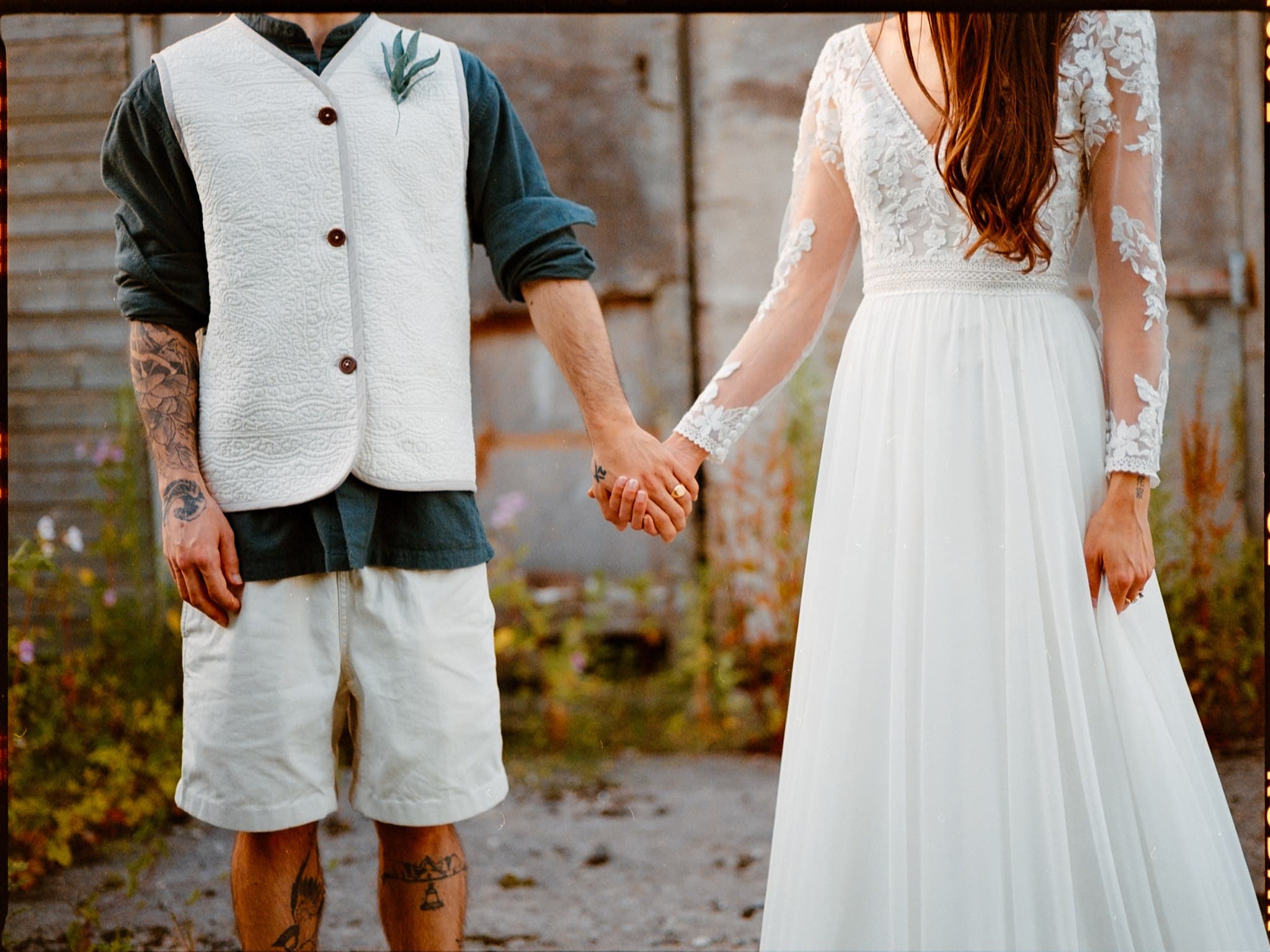 A film photo of A couple holding hands, woman in a lace wedding dress.