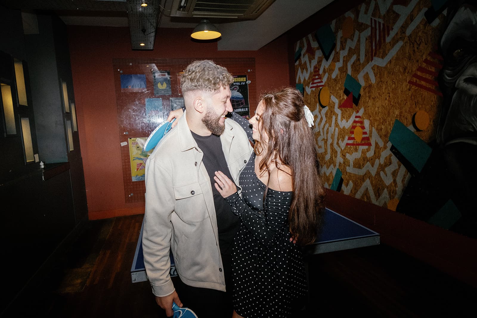 Two people embracing in front of a ping pong table
