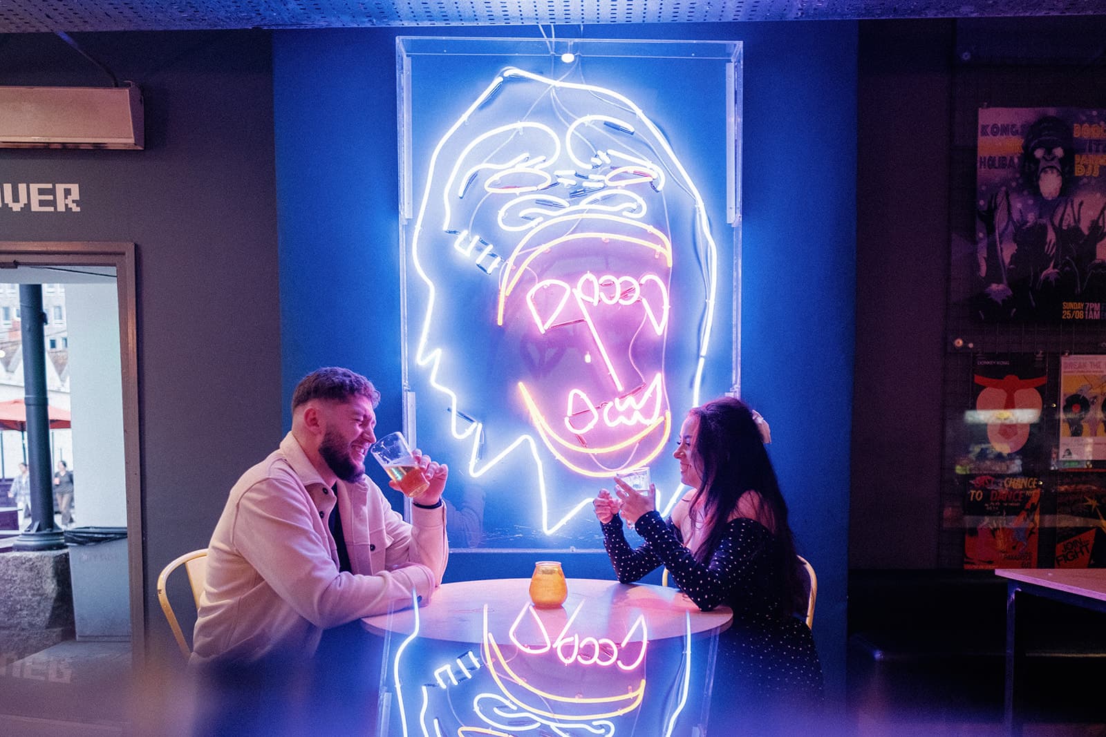 Two people sat in front of a neon sign in Kongs bristol