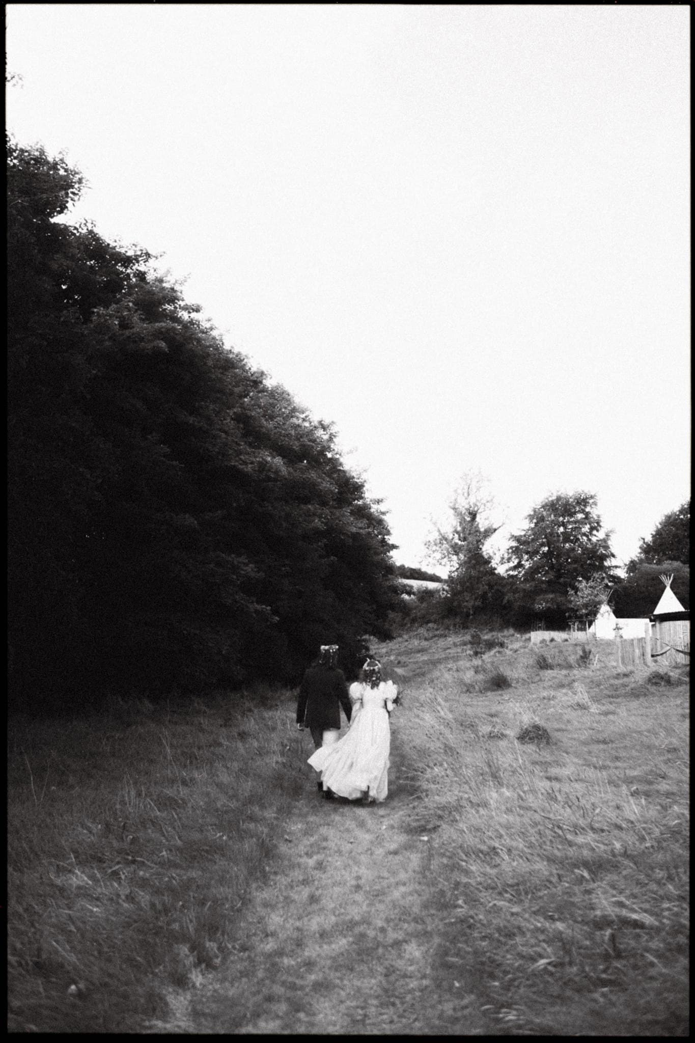 Bride and groom walking on a country path, black and white photo.
