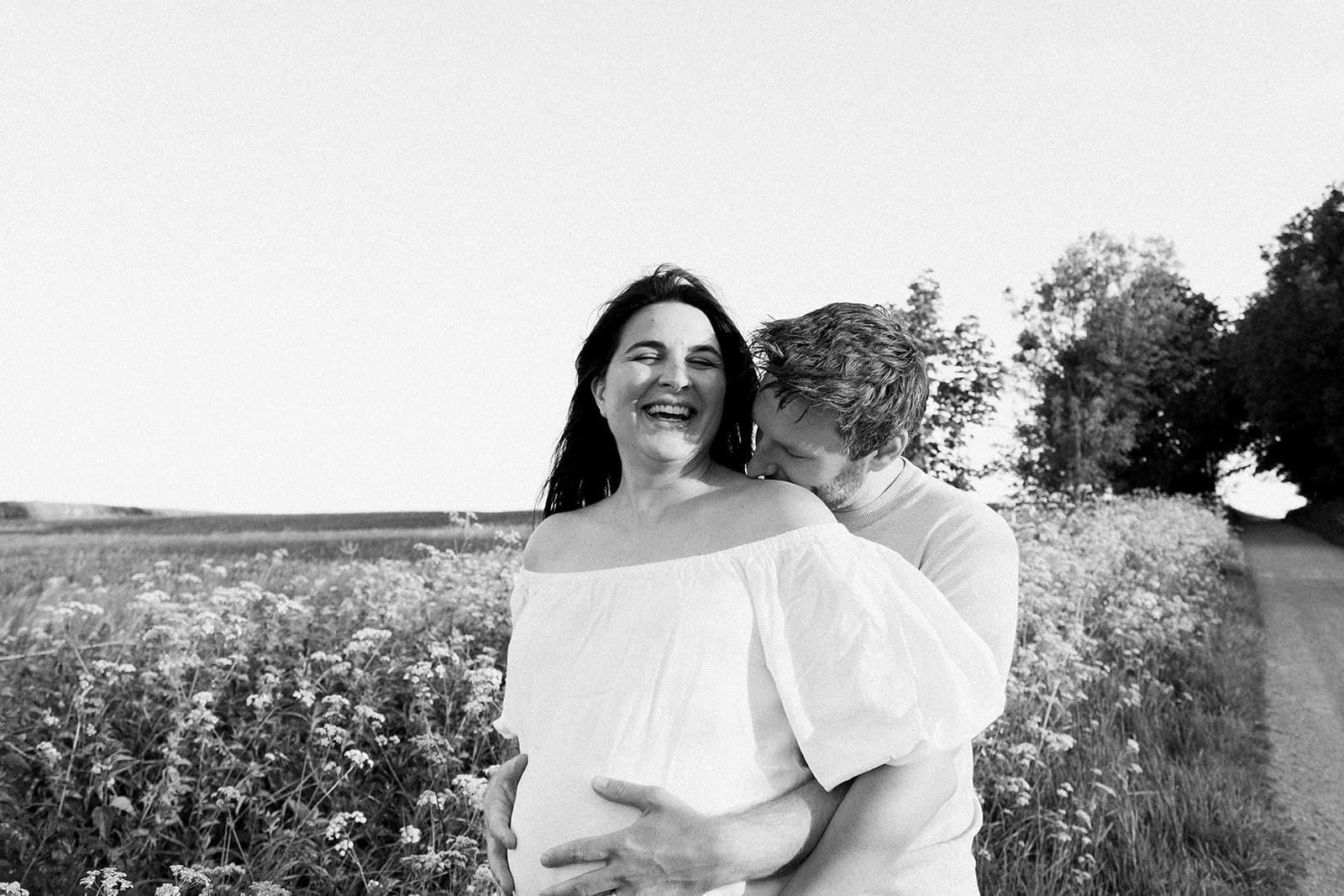 Two people embracing in a field with wildflowers, black and white photo.