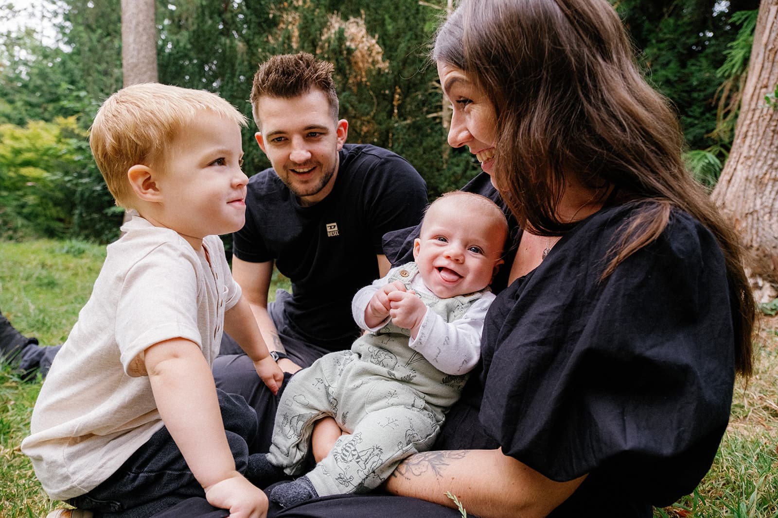 Family with two kids sitting on grass outdoors.