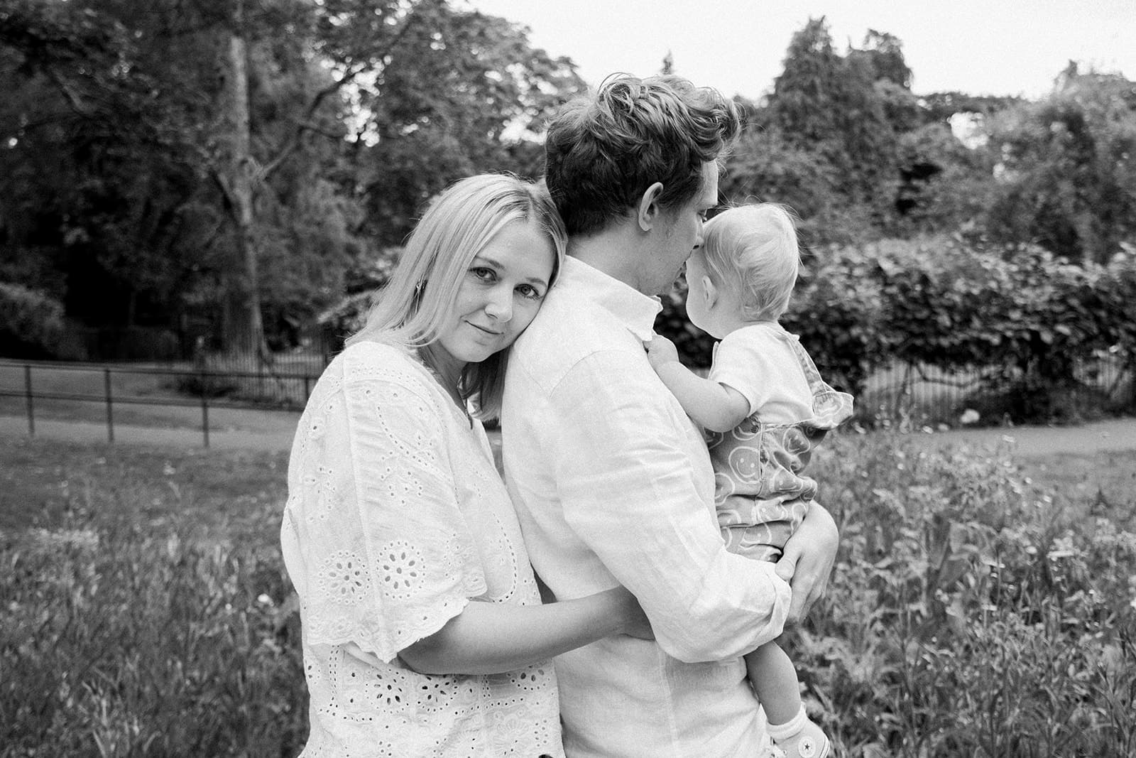 Family cuddling, mum cuddling dad from behind, mum looking into camera