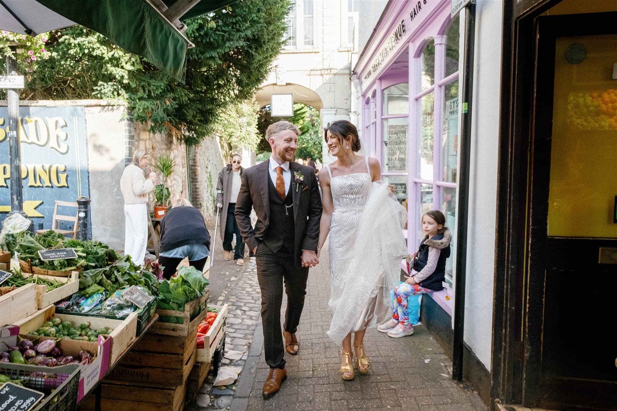 A wedding couple walking through a market street.