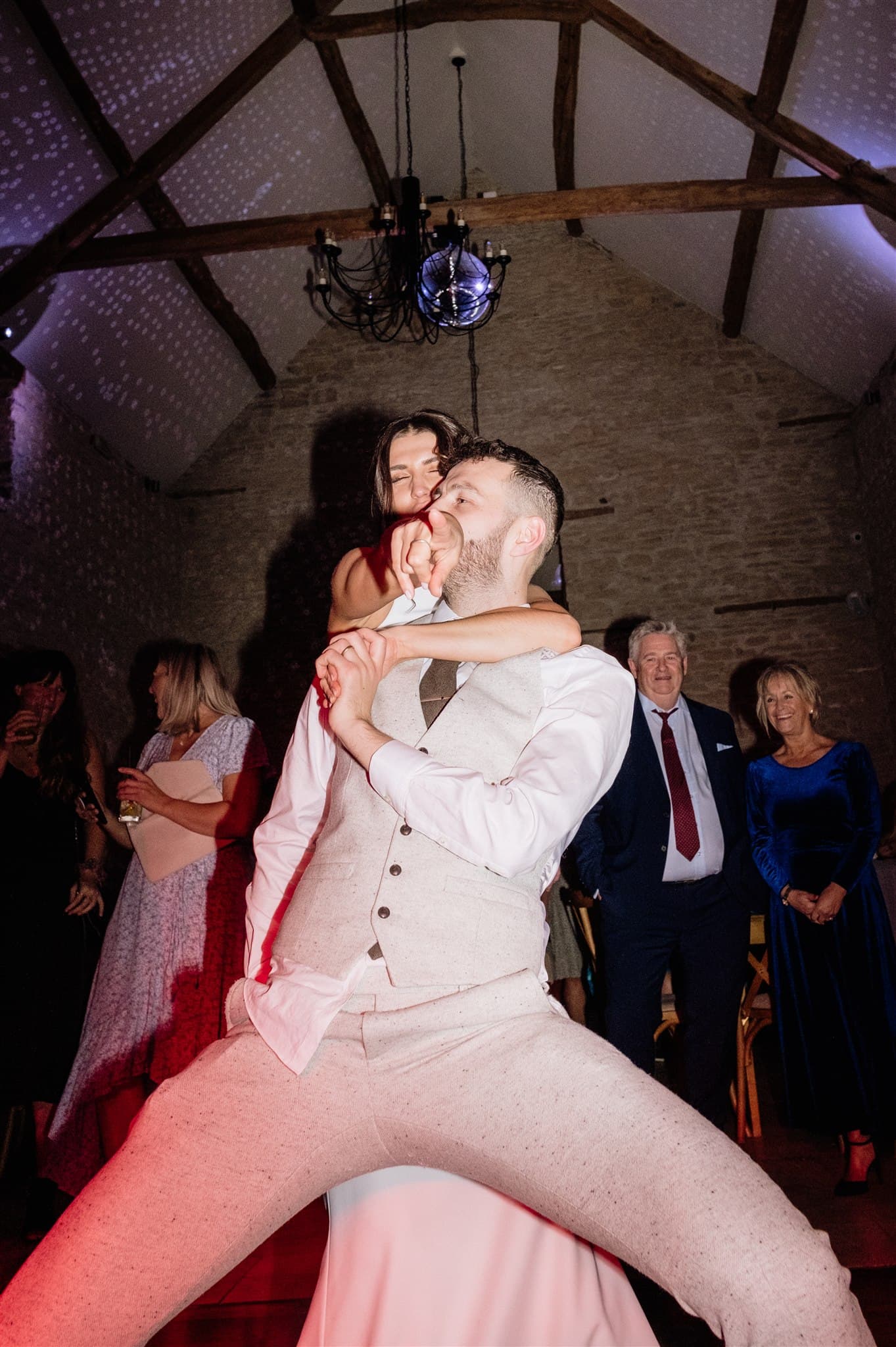 Bride and Groom dancing at a party with a disco ball and guests in the background.