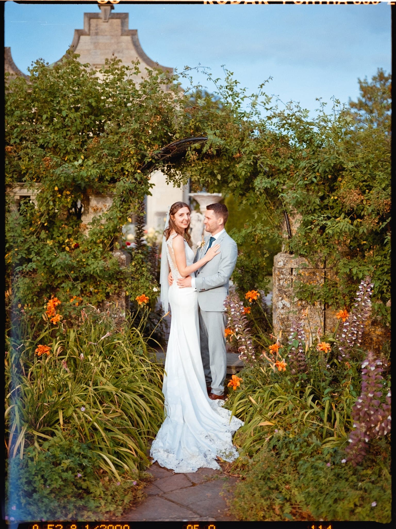 Film photo of A couple embracing in a garden, with a vintage aesthetic.